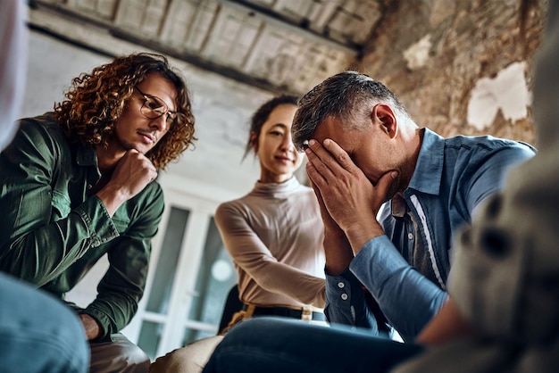 Psychotherapist working with group of drug addicted people at therapy session indoors