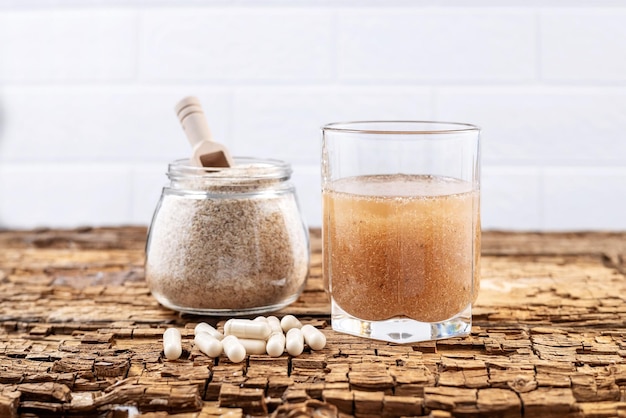 Psyllium 캡슐과 물 한 잔, 오래된 나무 판자에 있는 psyllium husk