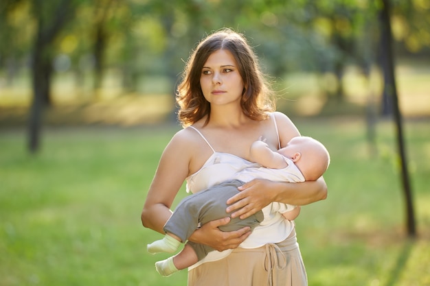 Public breastfeeding by young woman in public park with little child