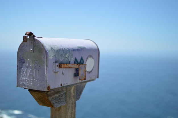 Foto scatola postale pubblica contro il mare contro il cielo blu