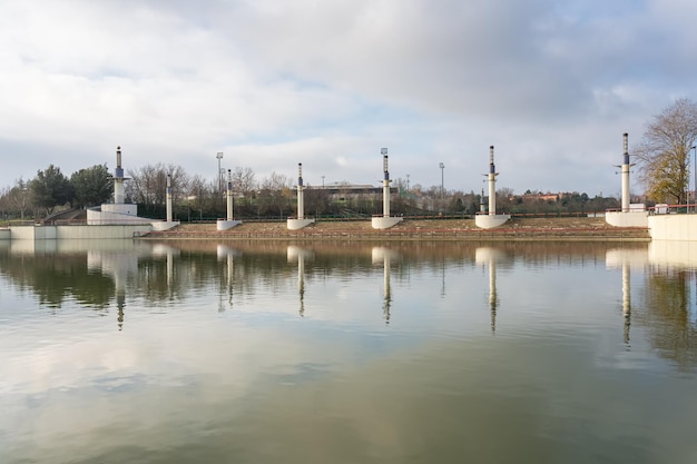 Общественный парк с большим озером, отражающим в воде декоративную архитектуру парка Tres Cantos Madrid.