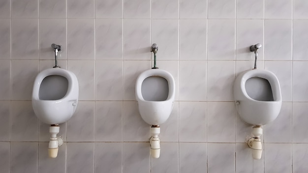 セラミック小便器がたくさんある公衆トイレ。大きな公衆トイレ、トイレに壁に取り付けられたボウル。小便器は男性用のボウルを用意します。