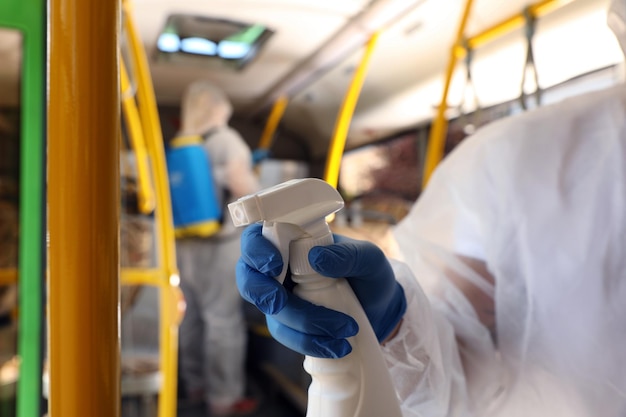 Public transport sanitation Worker in protective suit disinfecting bus salon closeup