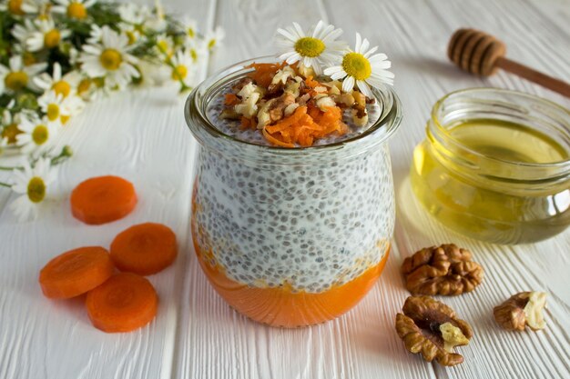 Pudding with chia, carrot, walnuts  and honey on the white wooden