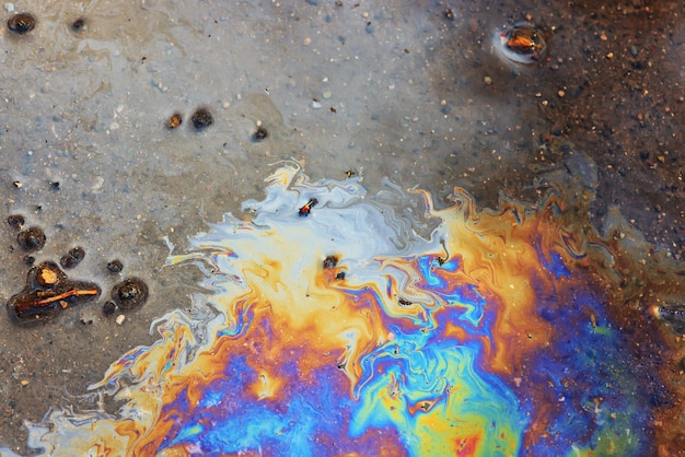 水たまりガソリンの背景、湿った油の色とりどりの虹の汚染の流出