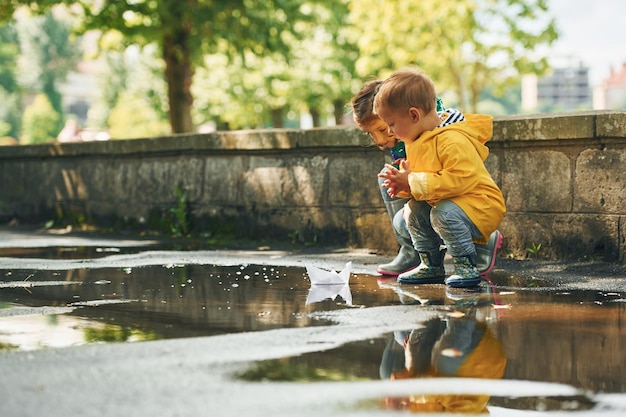 水たまりで 雨上がりの公園で外遊びする子供たち