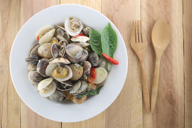 Puff meretrix or Meretrix casta is Seashell in white dish on wooden background.