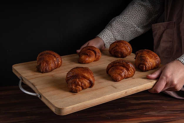 Foto panettiere di pasta sfoglia che mostra croissant vegani su una tavola di legno e sfondo nero