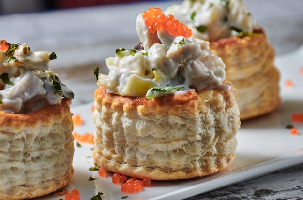 레드 캐비어로 장식 한 대구 샐러드로 채워진 퍼프 페이스트리 보트