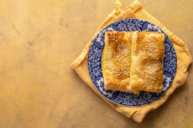 Puff pastry dough Folded baked puff pastry pie in a plate warm orange background