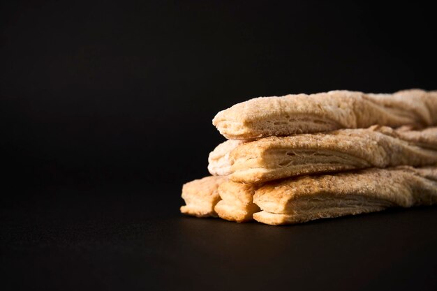 Puff pastry sticks with cinnamon on black background