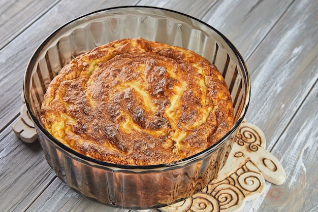 Puffed cauliflower souffle in transparent bowl on wooden background