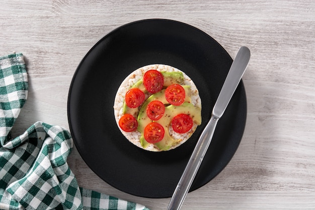 Puffed rice cake with tomato and avocado on wooden table