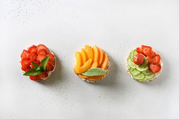 Torte di riso soffiato con diversi condimenti friuts e verdure su bianco. snack vegani.