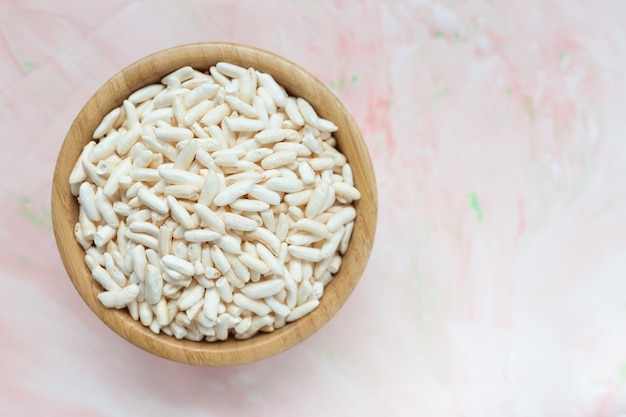 Puffed rice in a wooden bowl on pink 