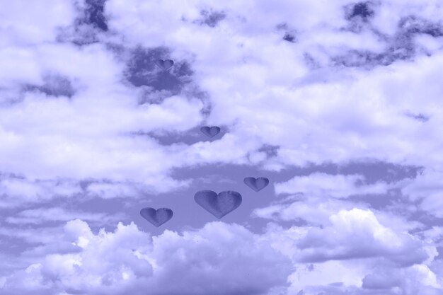 Puffy white clouds with hearts. cloudy sky abstract background\
toned in very peri copy space