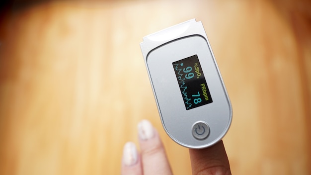 Pulse oximeter on finger showing oxygen saturation and heart rate