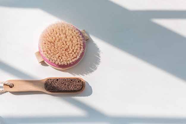 pumice and body brush on the white table in natural light.
