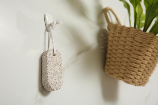 Pumice stone hanging on white wall space for text