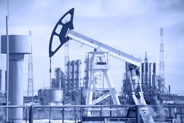 Pump jack on a background of petrochemical plant. Oil and gas industry. Toned.