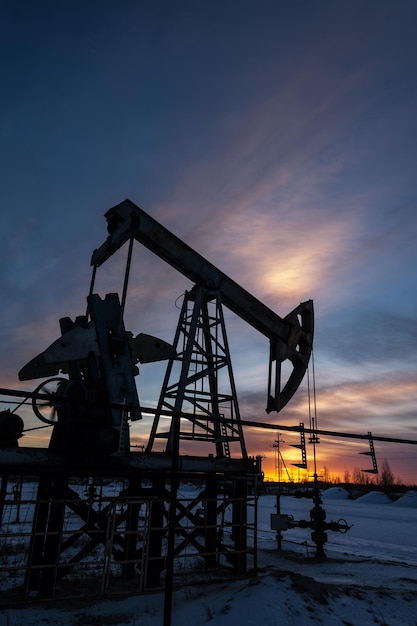 Pump jack at sunset sky background. Extraction of oil. Petroleum concept.