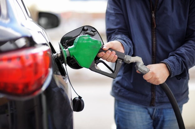 Pumping gas at gas pump. Closeup of man pumping gasoline fuel in car at gas station.