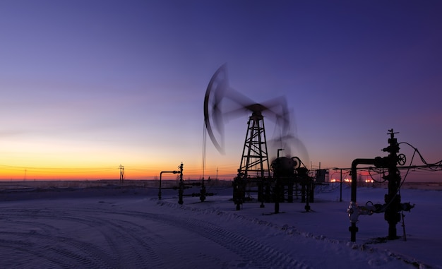 Foto pumpjack sullo sfondo del cielo al tramonto. esposizione prolungata. panorama.