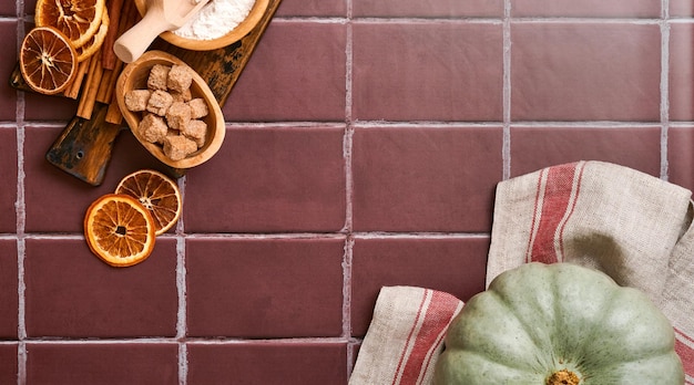 Pumpkin Autumn food background with cinnamon nuts and seasonal spices on old ceramic tiles background Cooking pumpkin or apple pie and cookies for Thanksgiving and autumn holidays Top view