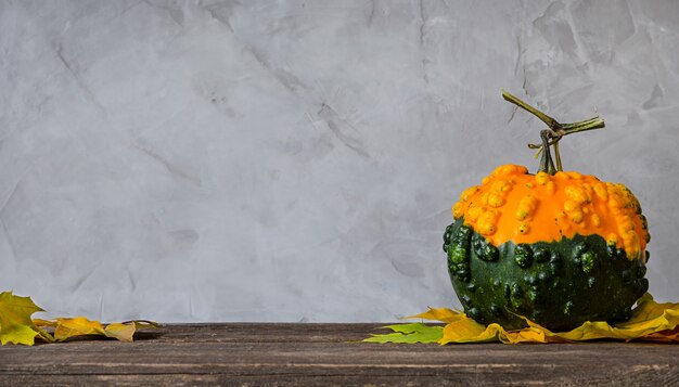 Pumpkin and autumn leaves on wooden table.