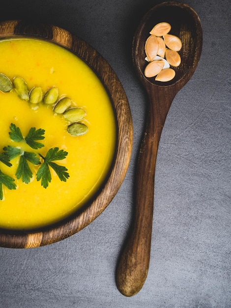 Pumpkin autumn soup in wooden bowl with parsley seeds dietary vegetable vegan food