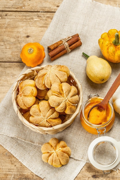 Pumpkin buns or biscuits, traditional fall baked goods. Seasonal homemade food and autumn decor. Old wooden boards background, top view