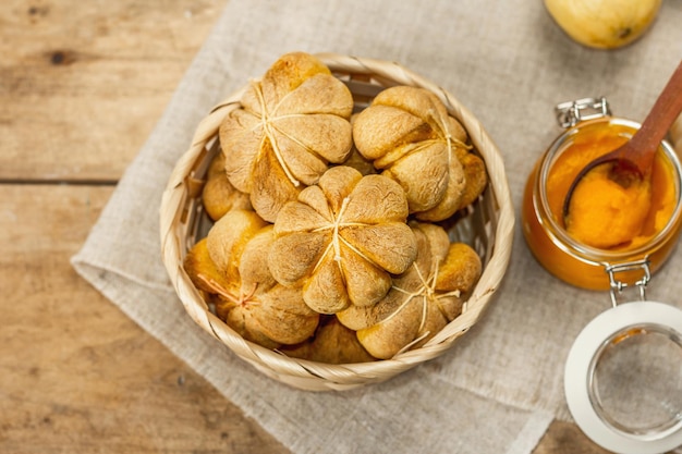 Pumpkin buns or biscuits, traditional fall baked goods. Seasonal homemade food and autumn decor. Old wooden boards background, top view