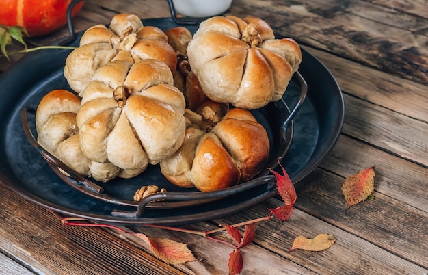Тыквенные булочки, хлеб с корицей на ретро-подносе на деревенском деревянном фоне. Осенняя еда на Хэллоуин.