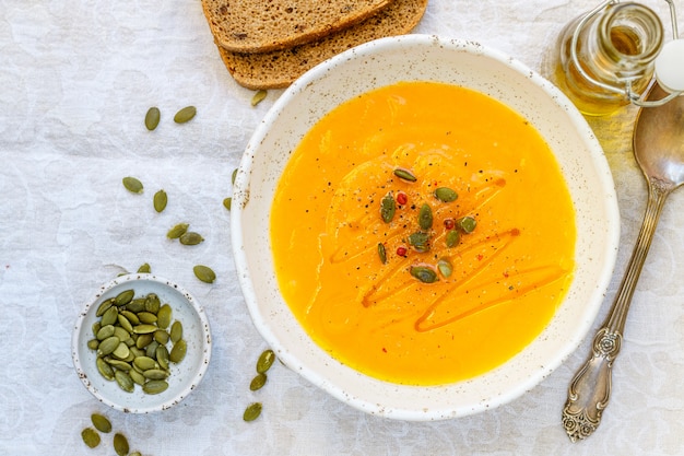 Pumpkin and carrot puree soup with seeds, pink pepper and olive oil