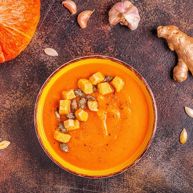 Photo pumpkin and carrot soup served with seeds, top view.