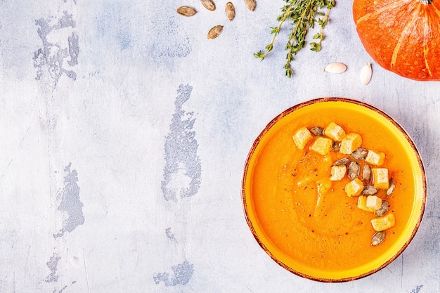 Pumpkin and carrot soup served with seeds, top view.