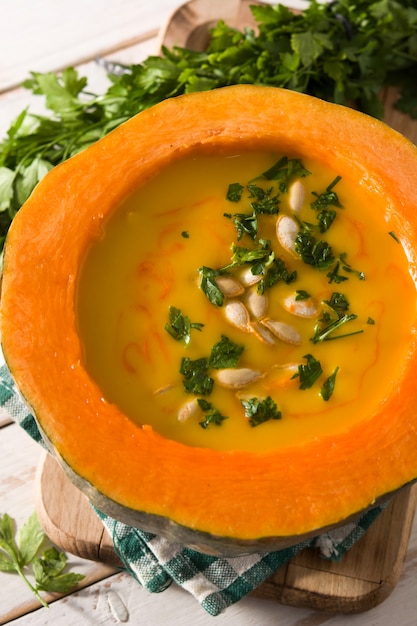 Pumpkin and carrot soup on white wooden table.