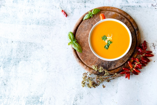 Pumpkin and carrot soup with cream on grey stone