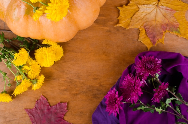 Pumpkin, chrysanthemum flowers and dry autumn leaves