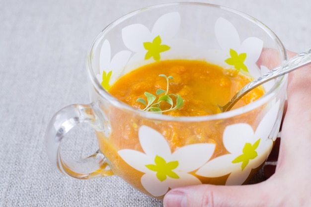 Pumpkin cream soup in a glass bowl and sour cream