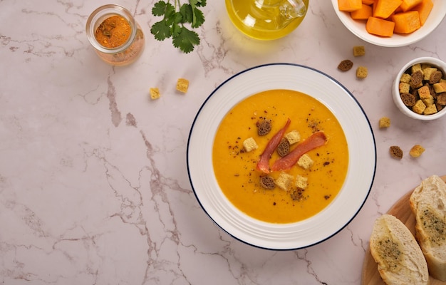 Pumpkin cream soup on a light marble background