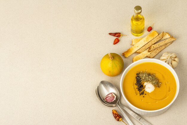 Pumpkin cream soup. Traditional autumn food. Hot dish, ripe vegetables, fragrant spices. Light stone concrete background, copy space