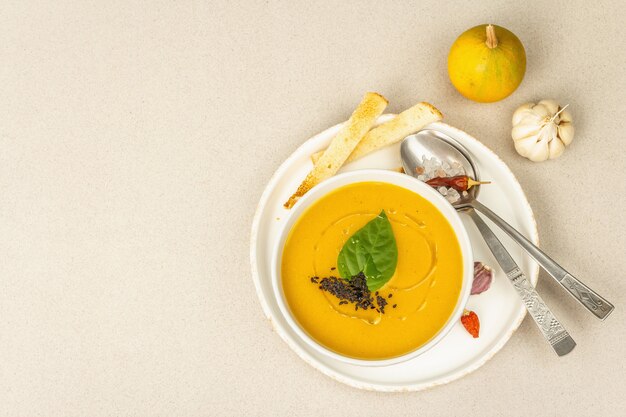 Pumpkin cream soup. Traditional autumn food. Hot dish, ripe vegetables, fragrant spices. Light stone concrete background, top view