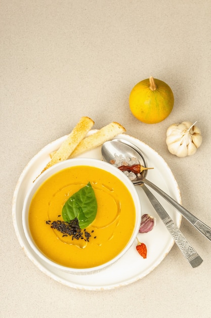 Pumpkin cream soup. Traditional autumn food. Hot dish, ripe vegetables, fragrant spices. Light stone concrete background, top view