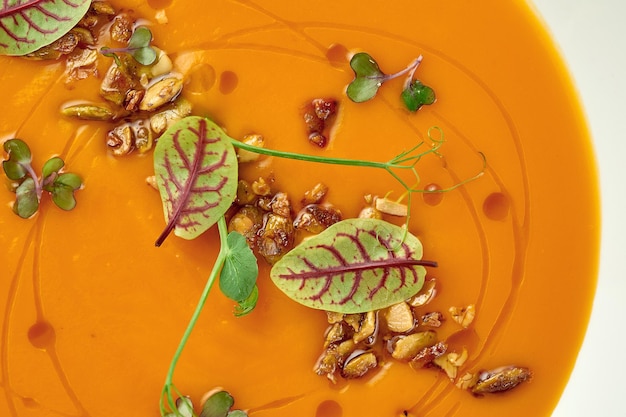 Pumpkin cream soup in a white plate on a white tablecloth