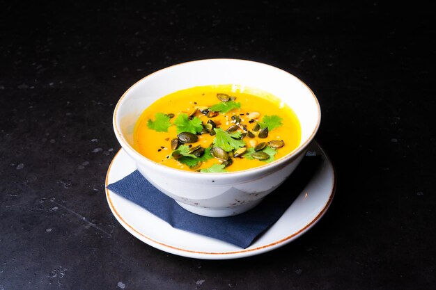 Pumpkin cream soup with parsley on gray stone and wooden background top view copy space