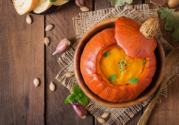 Pumpkin cream soup with peppers and herbs in a pumpkin