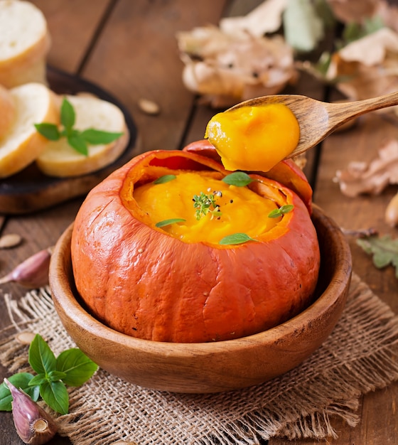 Pumpkin cream soup with peppers and herbs in a pumpkin