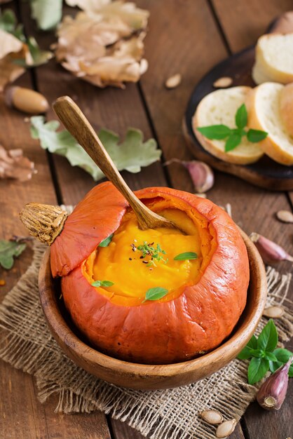 Foto zuppa di crema di zucca con peperoni ed erbe aromatiche in una zucca