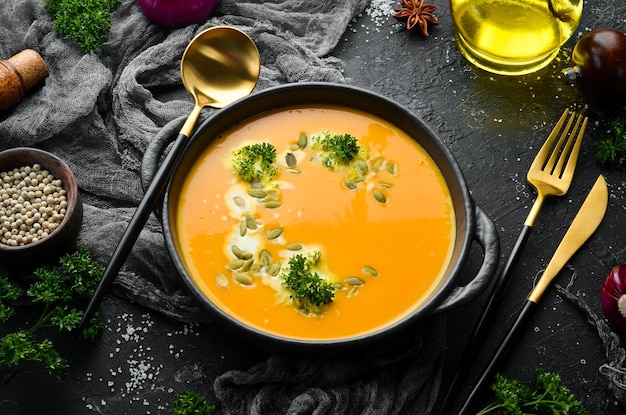 Pumpkin cream soup with pumpkin seeds in a black stone plate Autumn menu Diet Top view Free space for text